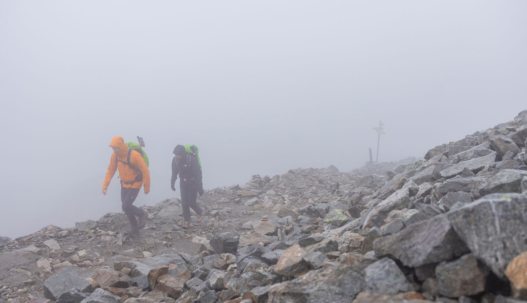 Twee wandelaars lopen in de mist op een berg.