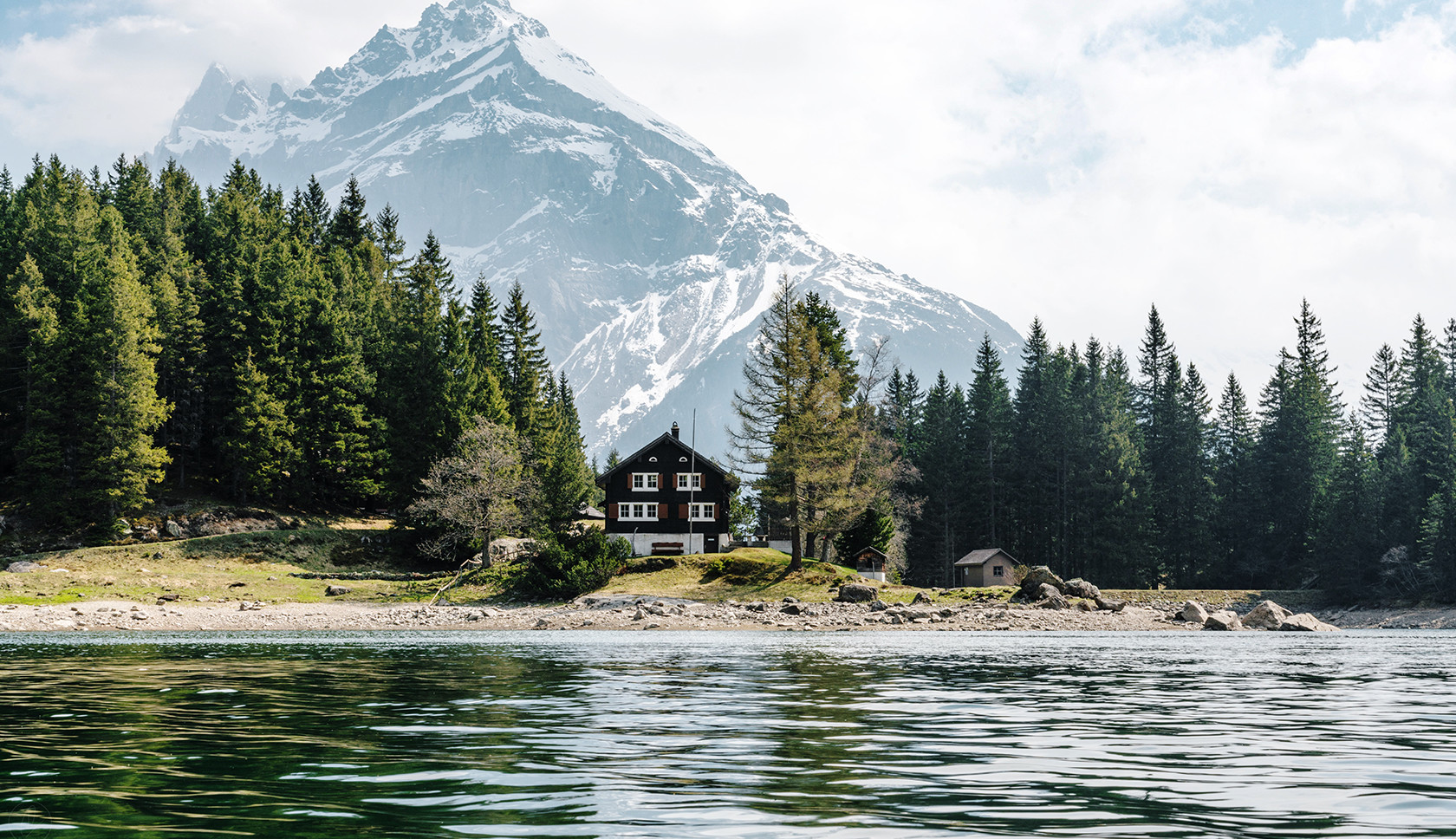 een huis langs het water in Zwitserland, op de achtergrond staat een berg