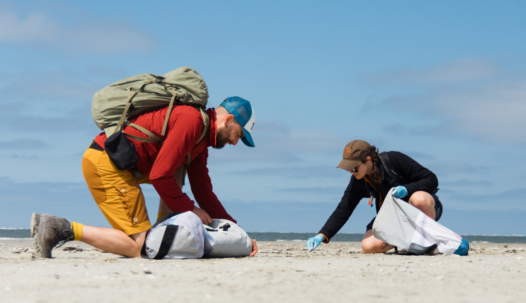 een man en een vrouw ruimen zwerfafval op op het strand