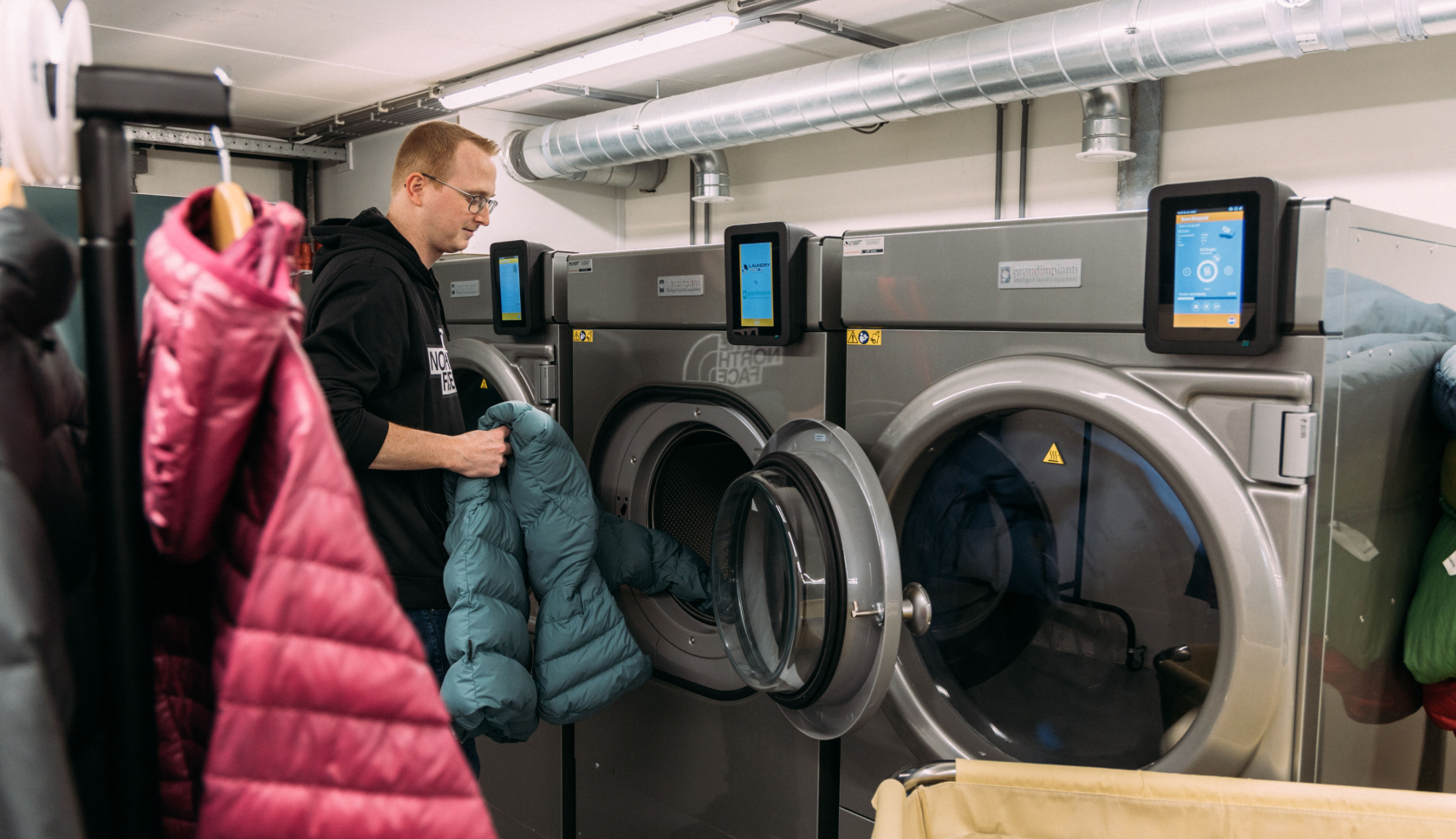 een man stopt een donsjas in de wasmachine