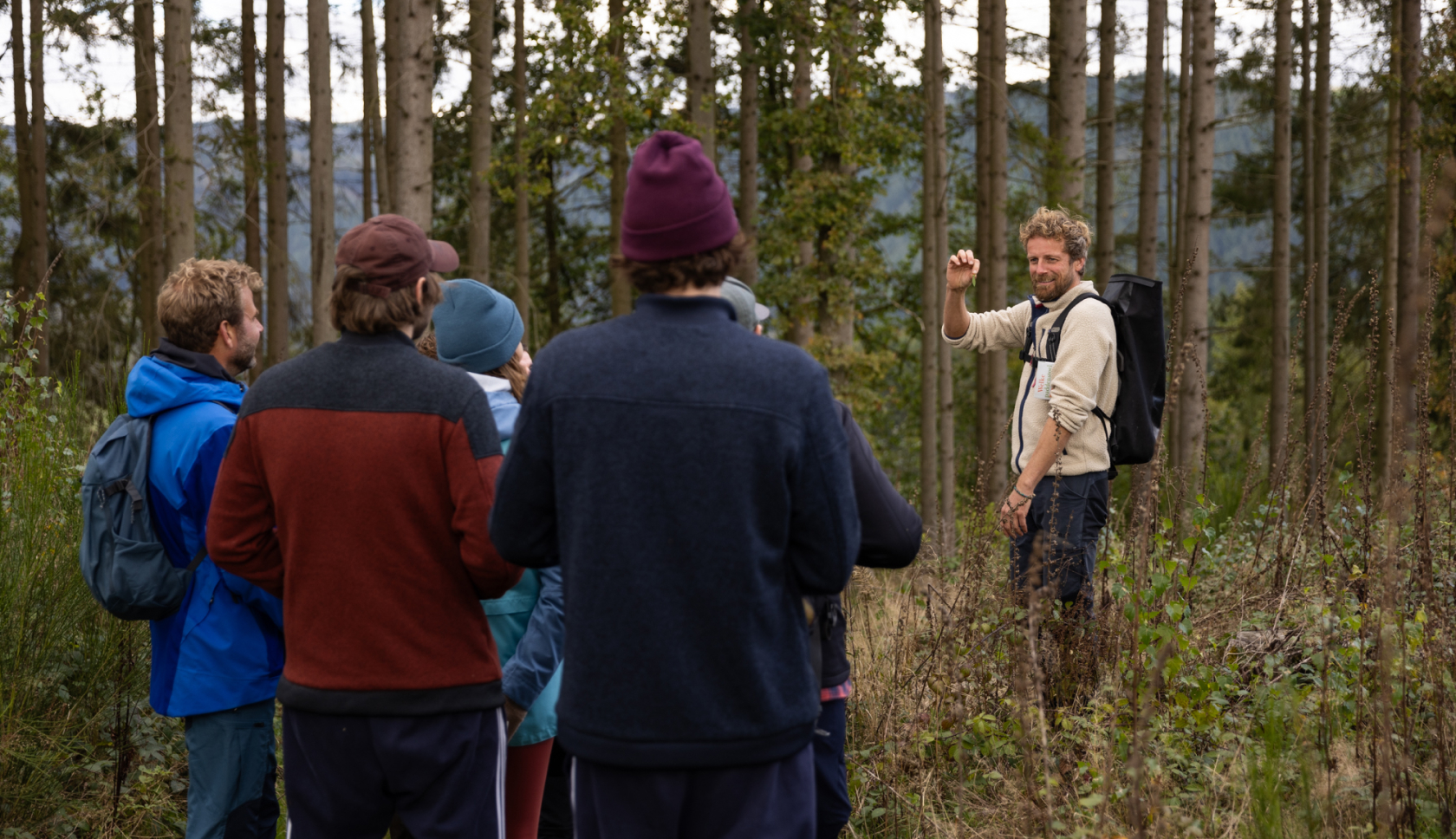 Een man in het bos laat iets zien aan een groep mensen