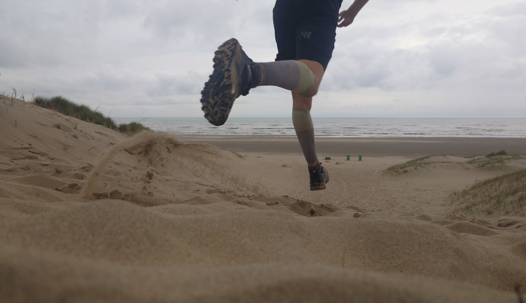 een man loopt een zandduin af de zee tegemoet