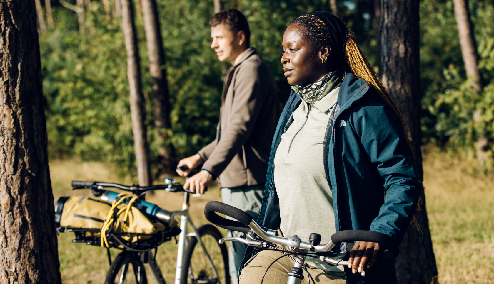 Een man en vrouw staan met de fiets in de hand in een bos