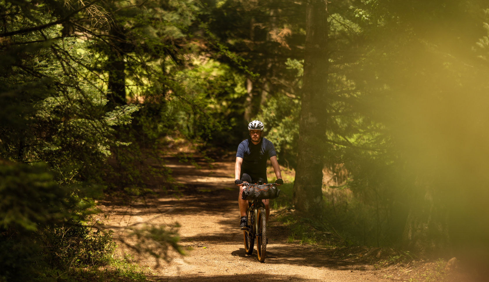 Een man fietst rustig door het bos op een gravelbike