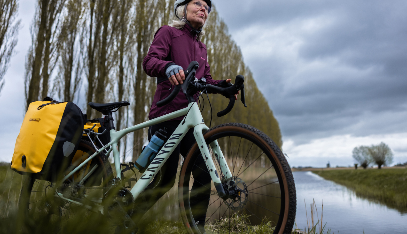 een vrouw staat met haar fiets langs een sloot