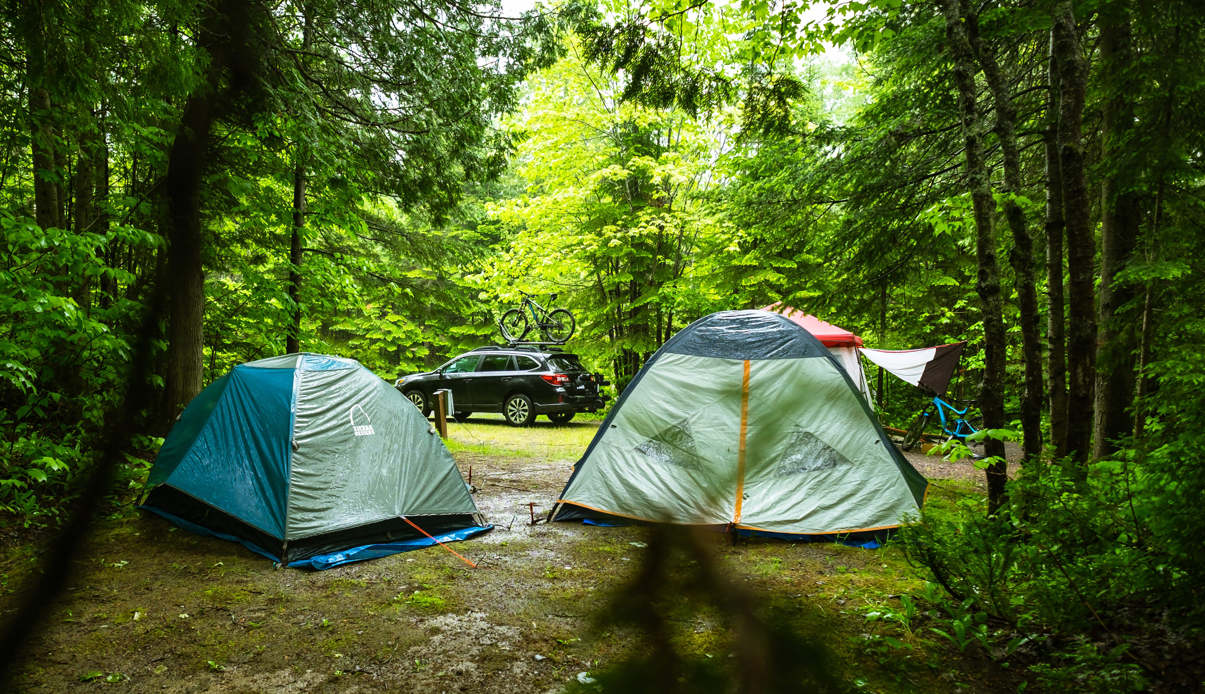 een tent staat naast een auto op een camping 