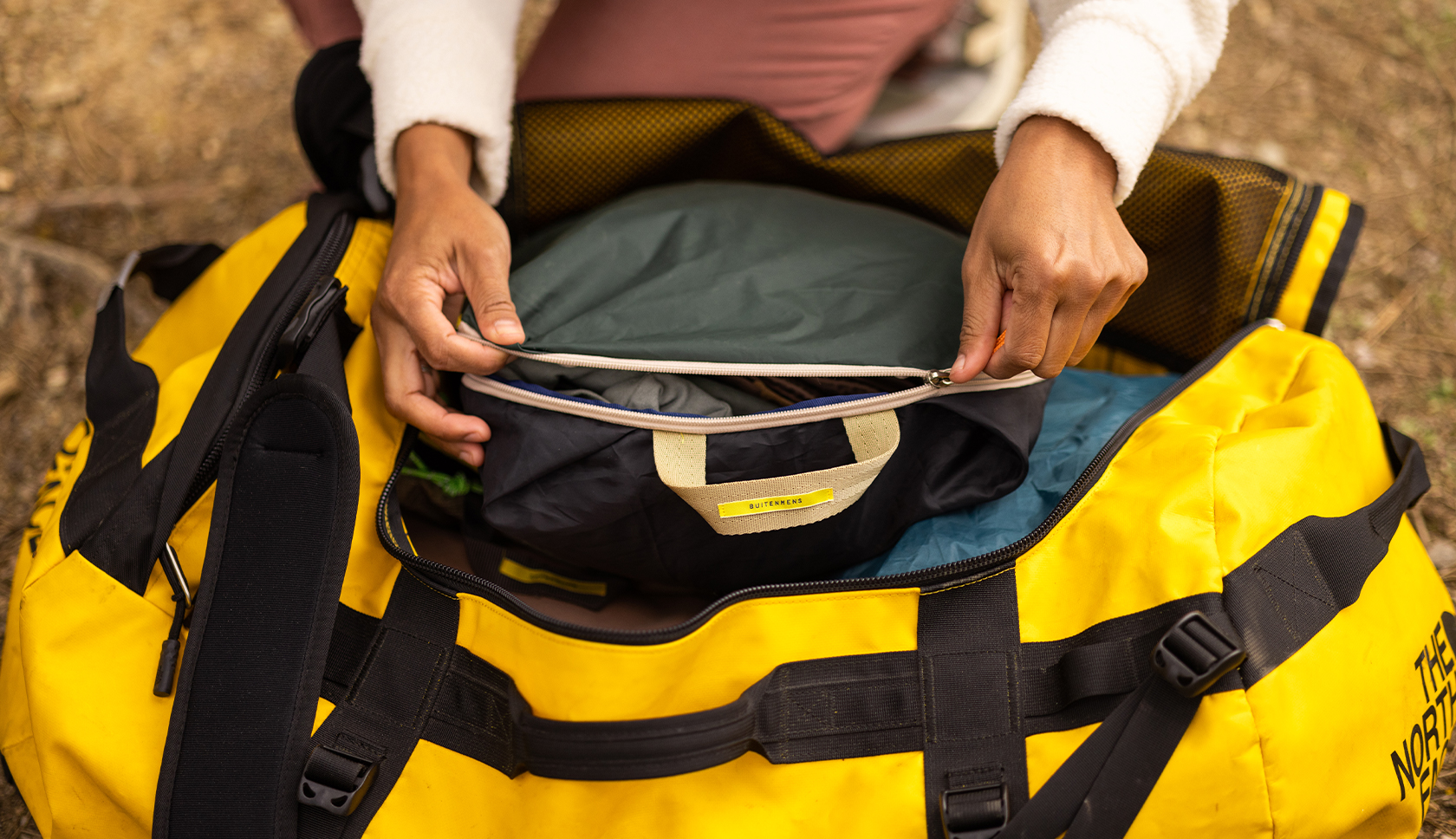 een persoon haalt een toilettas uit een duffel bij het uitpakken 