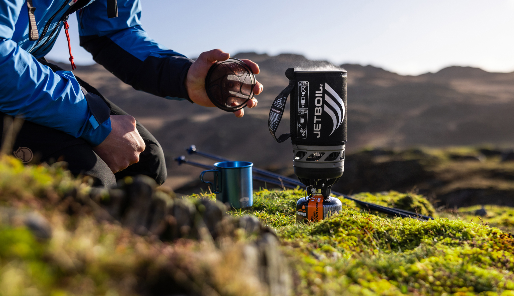 Een jetboil-brander staat op een mossige ondergrond