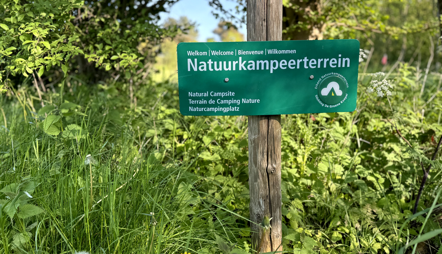 Een groen informatiebordje over natuurkampeerterrein