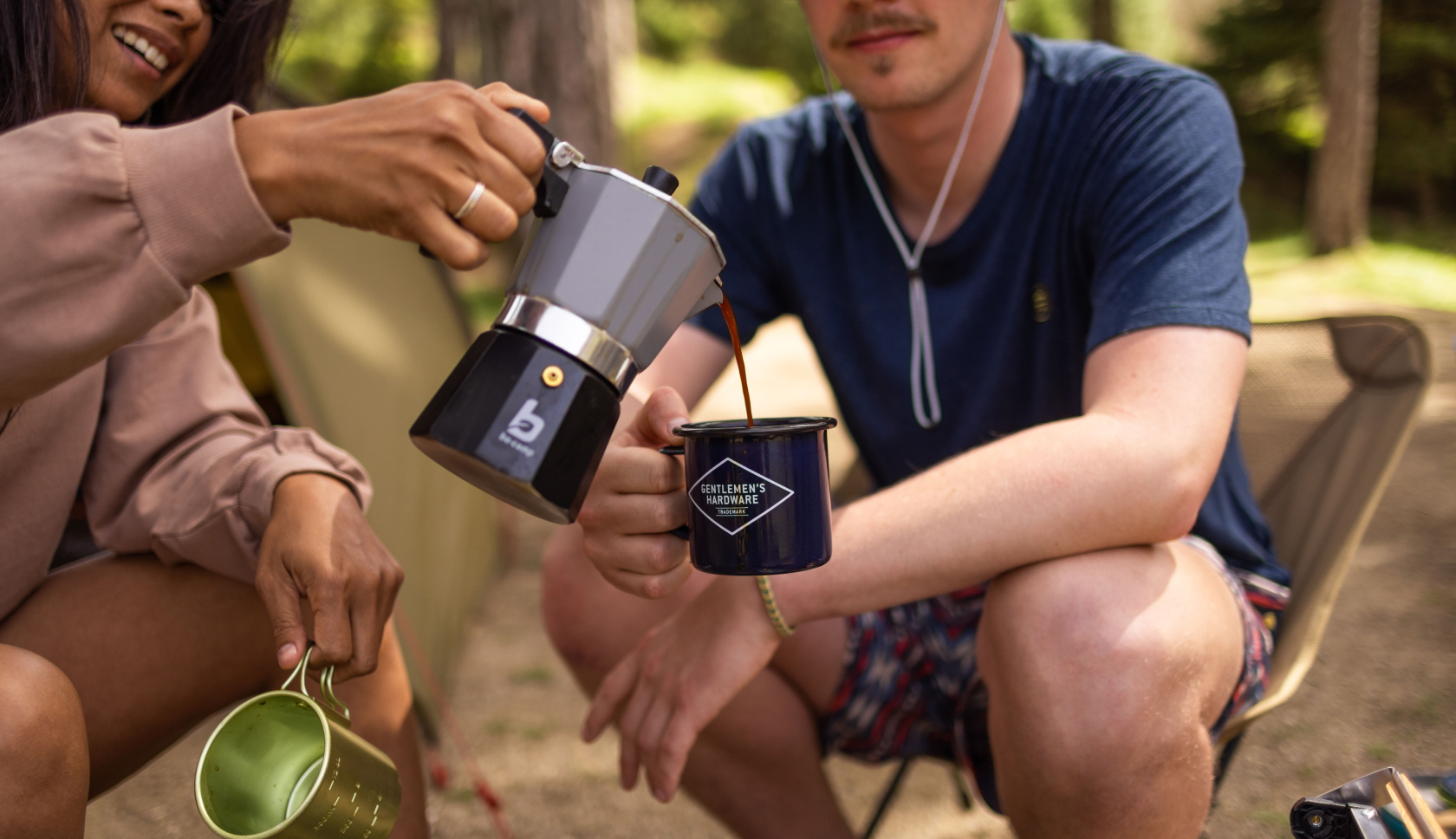 een vrouw schenkt een kop koffie in bij een man op de camping