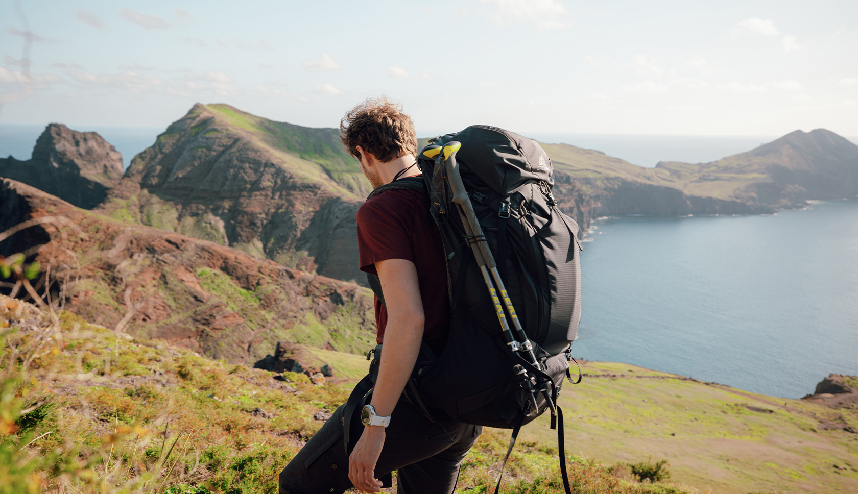 man met trekkingrugzak loopt door een heuvelachtig landschap