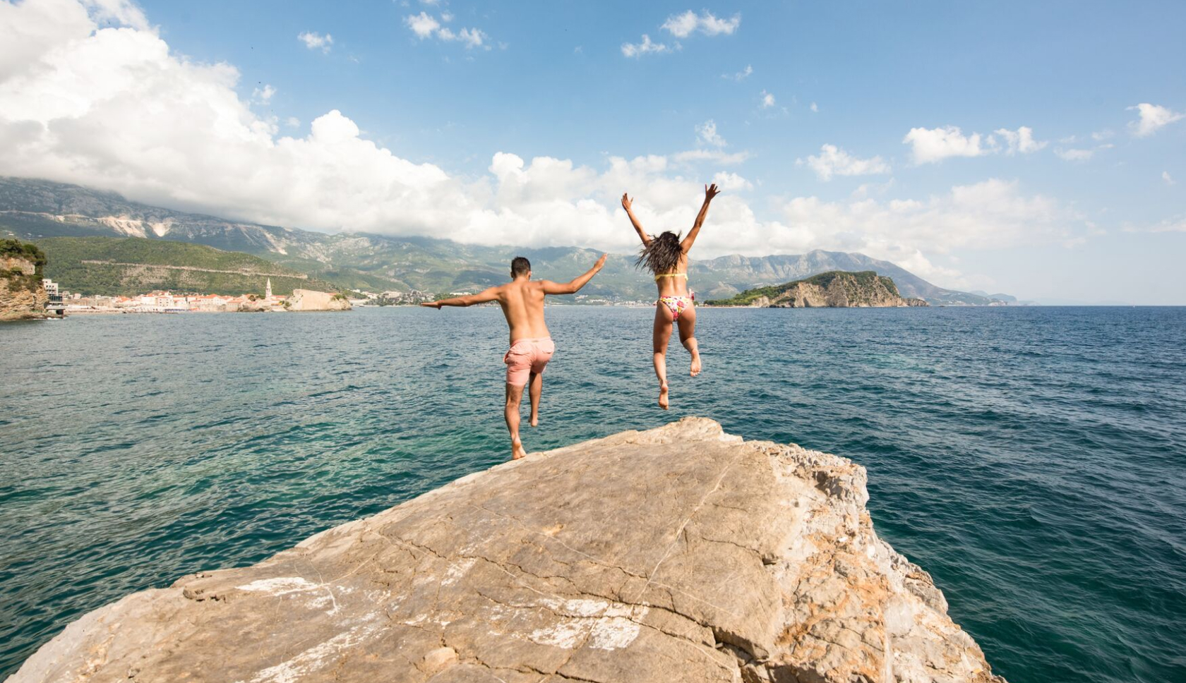 Een man en vrouw springen van een klif in het water