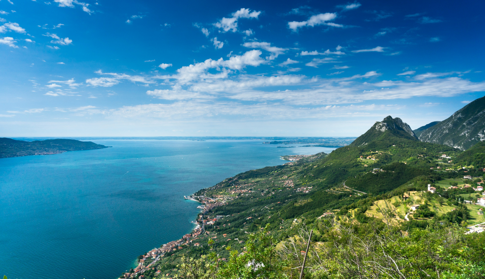 een blauw meer met groene hellingtoppen langs de oever