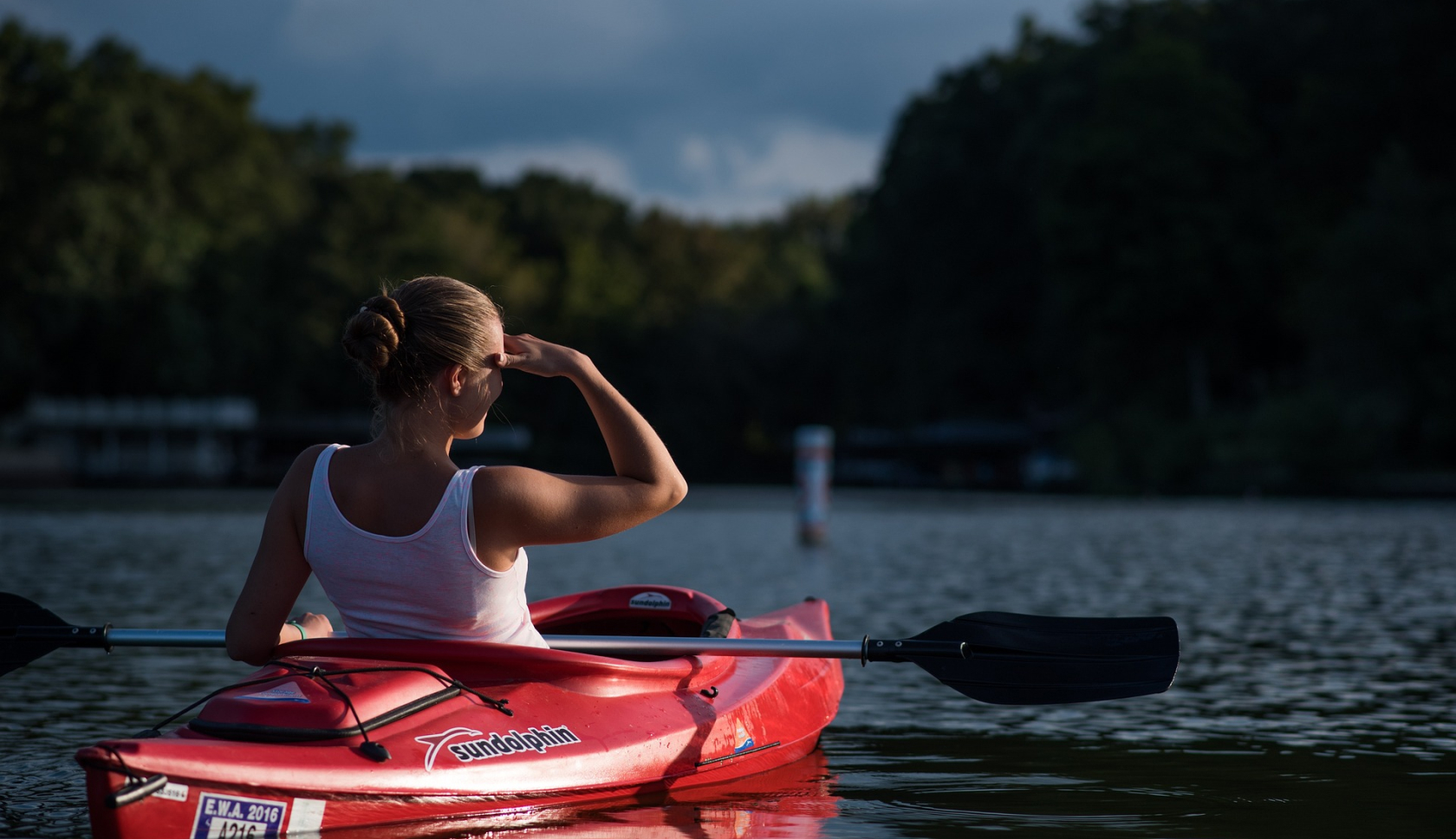 een kajakkende vrouw tuurt over het water