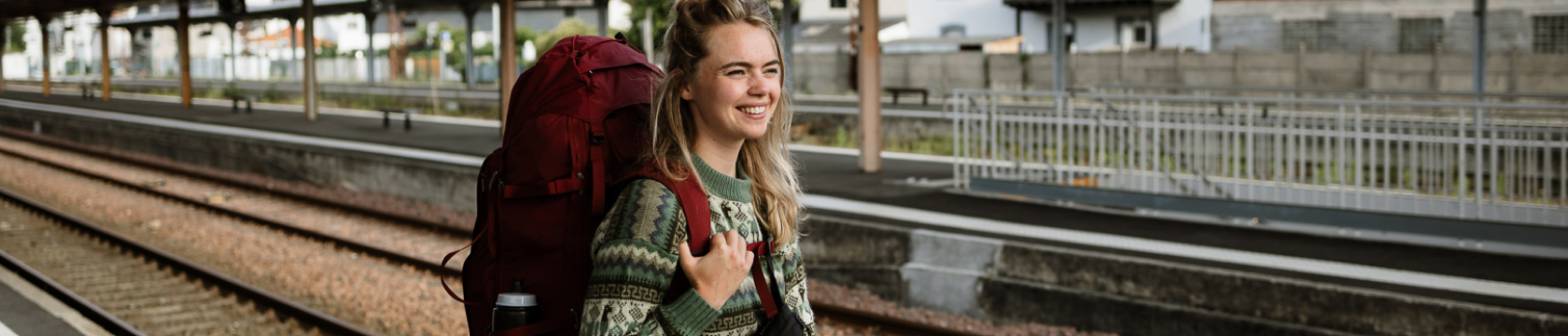 Een jonge vrouw met backpack staat op het station