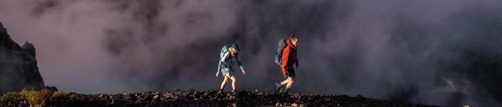 Een jonge vrouw en man wandelen hoog in de bergen