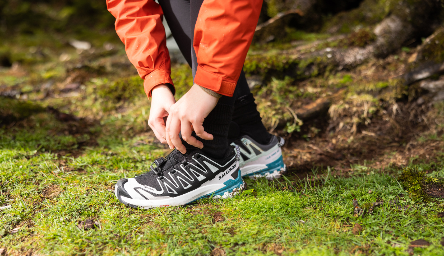 Iemand strikt de veters van lage, zwarte wandelschoenen in het bos