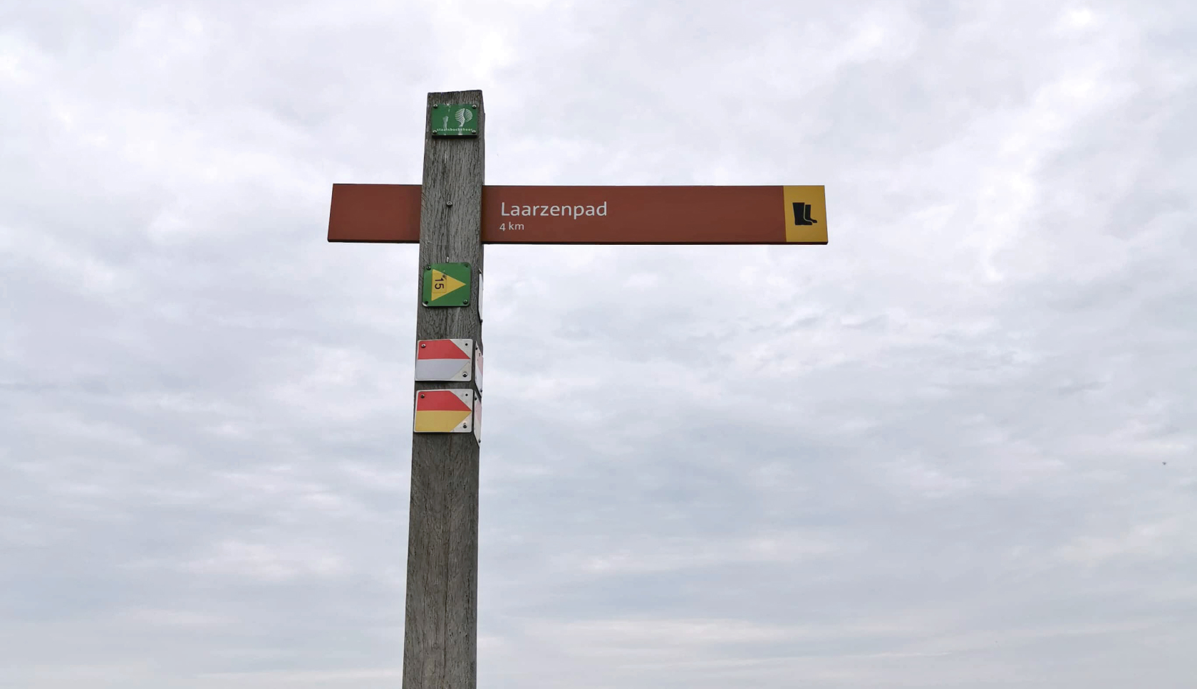 Een houten routebord met de tekst 'laarzenpad' wijst naar rechts