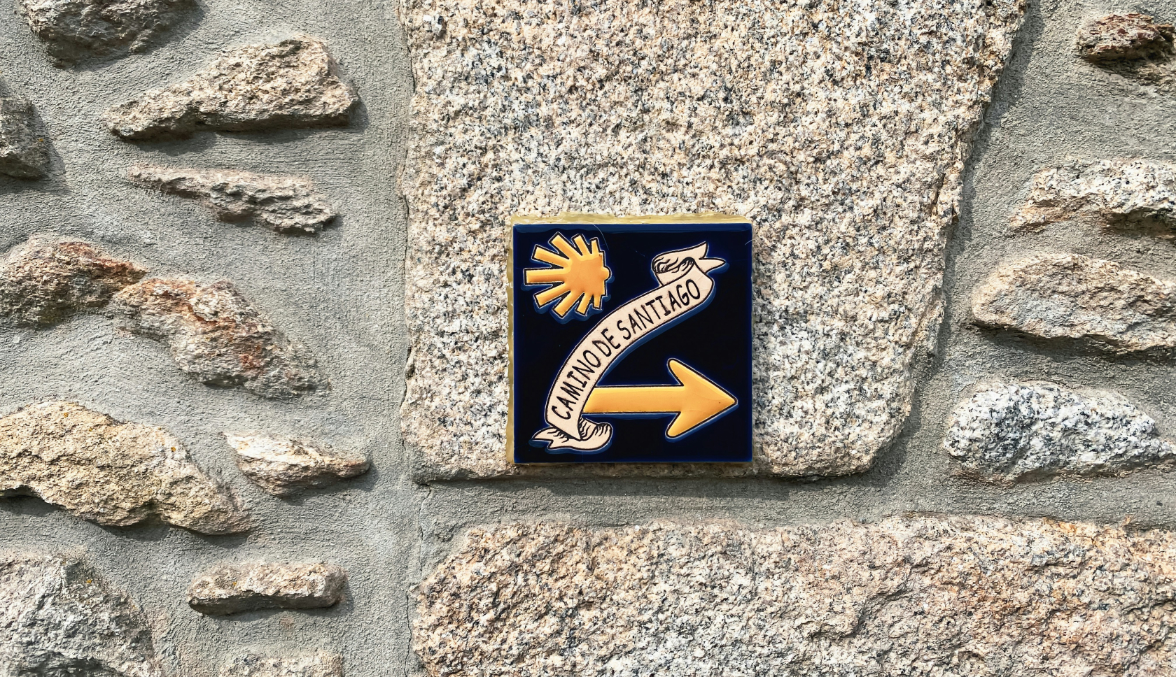 Een stenen muur met een bordje dat leest: camino de santiago