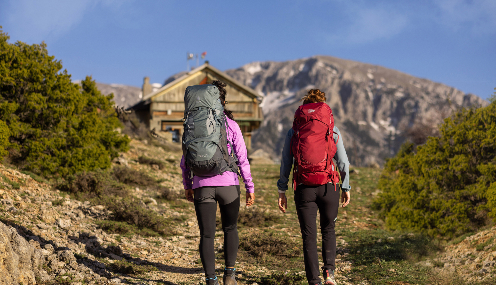 Twee vrouwen met een rugzak lopen in de bergen