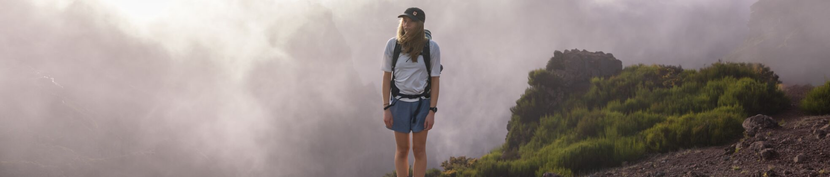 Een jonge vrouw staat in de bergen, omhuld door wolken