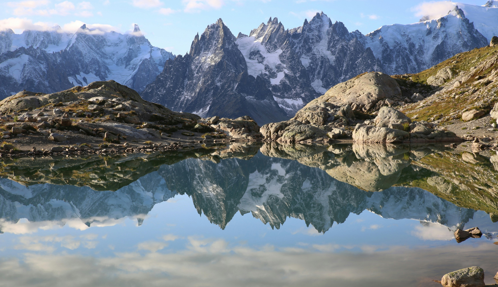 Een bergmeer weerspiegelt een blauwe lucht en bergpieken