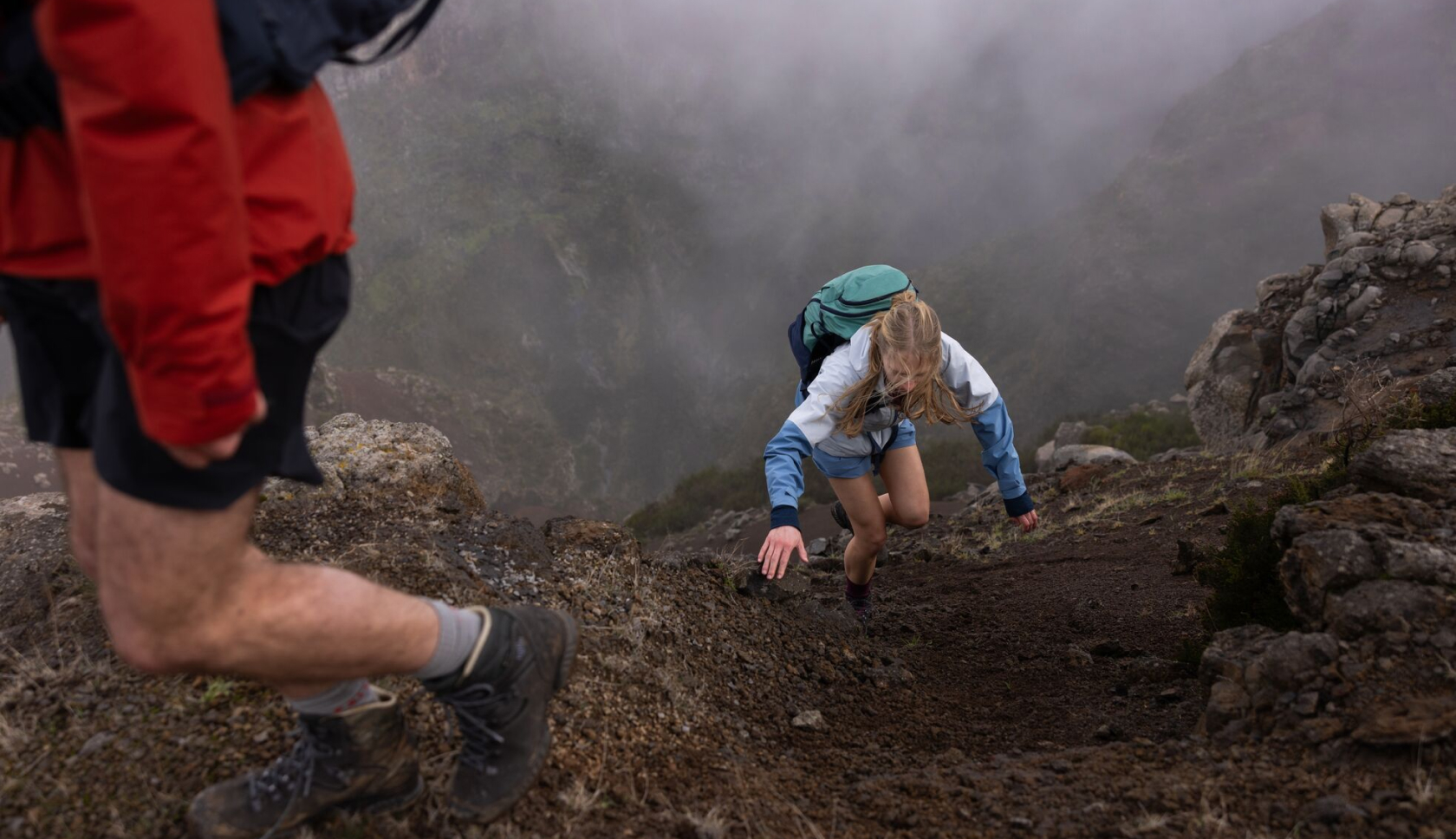 Een jonge vrouw klautert omhoog op een steile bergwand