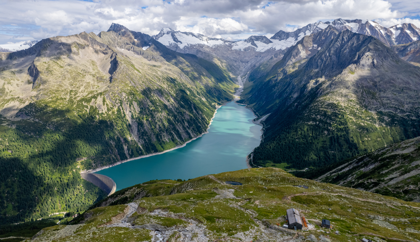 De helderblauwe Schlegeis Stausee, omringd door besneeuwde bergtoppen