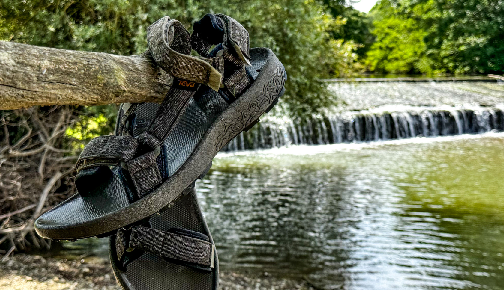 een paar sandalen hangen aan een tak voor een kleine waterval