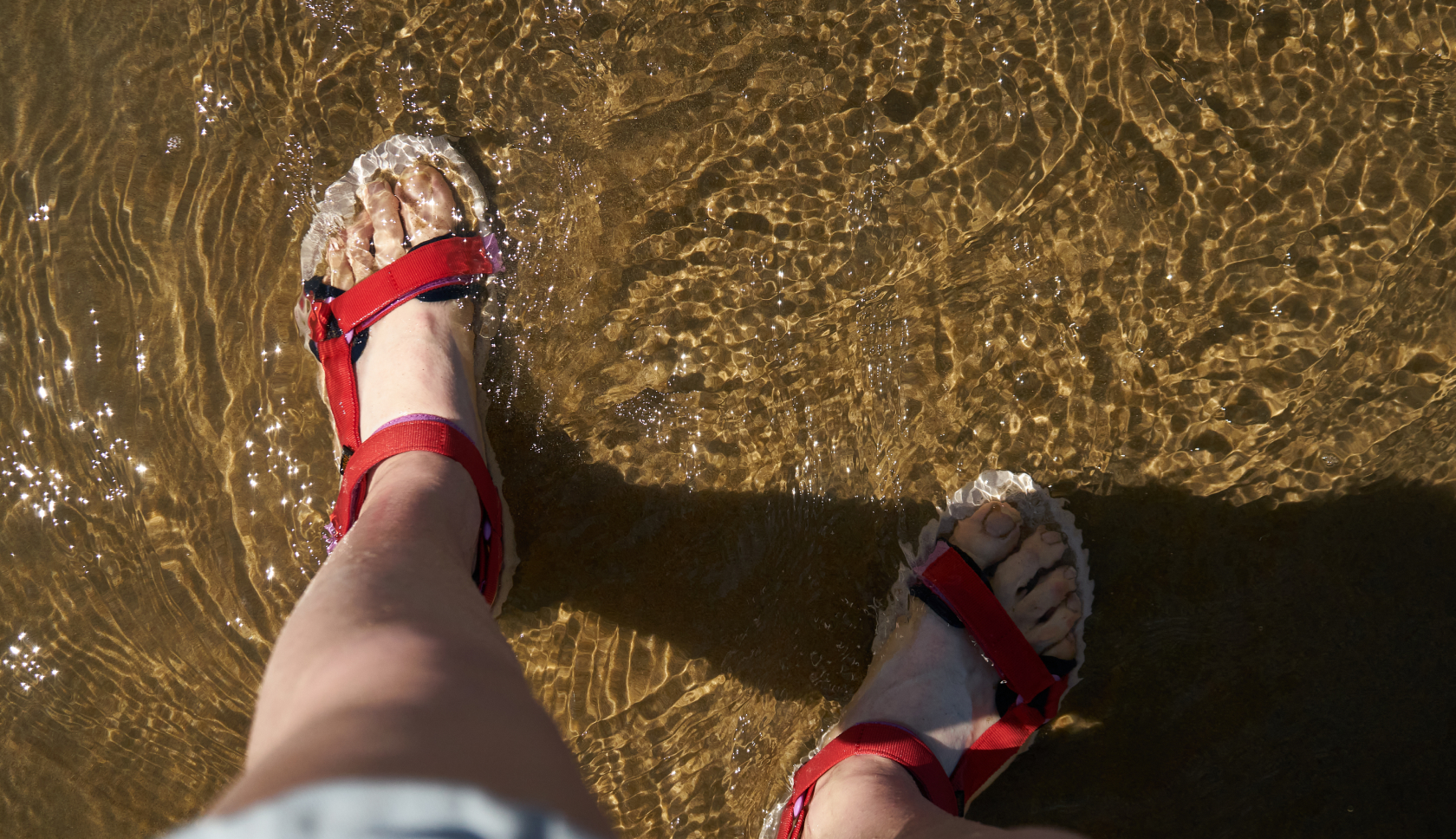 een persoon staat met sandalen in het water