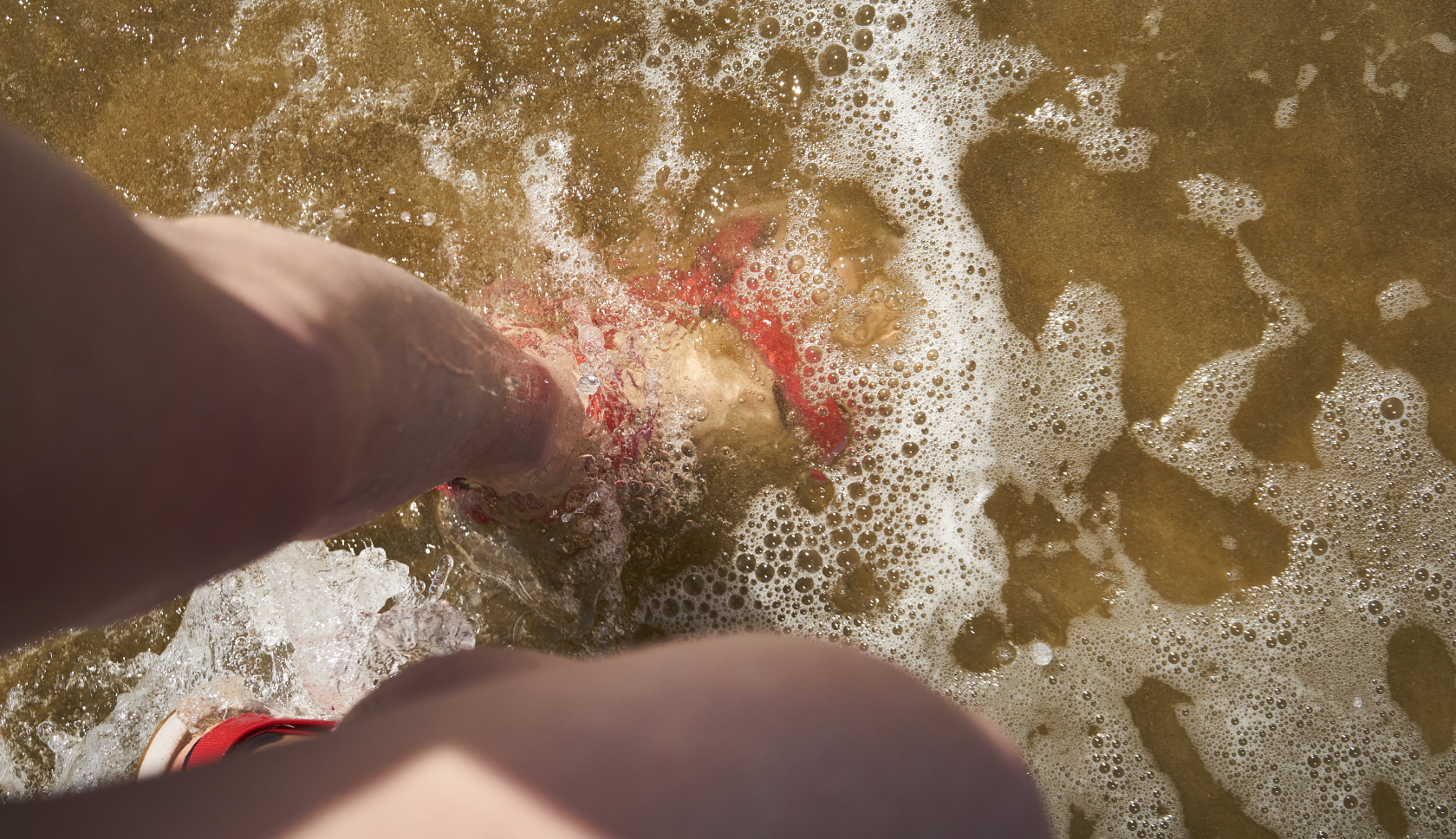 een vrouw staat met sandalen in het water