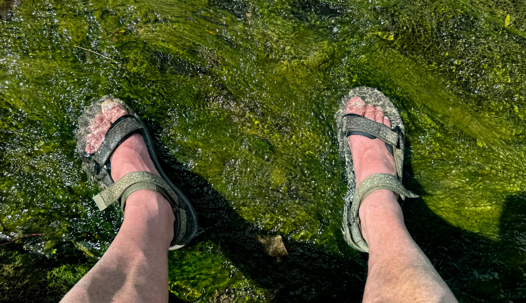 een man staat met sandalen in een rivier