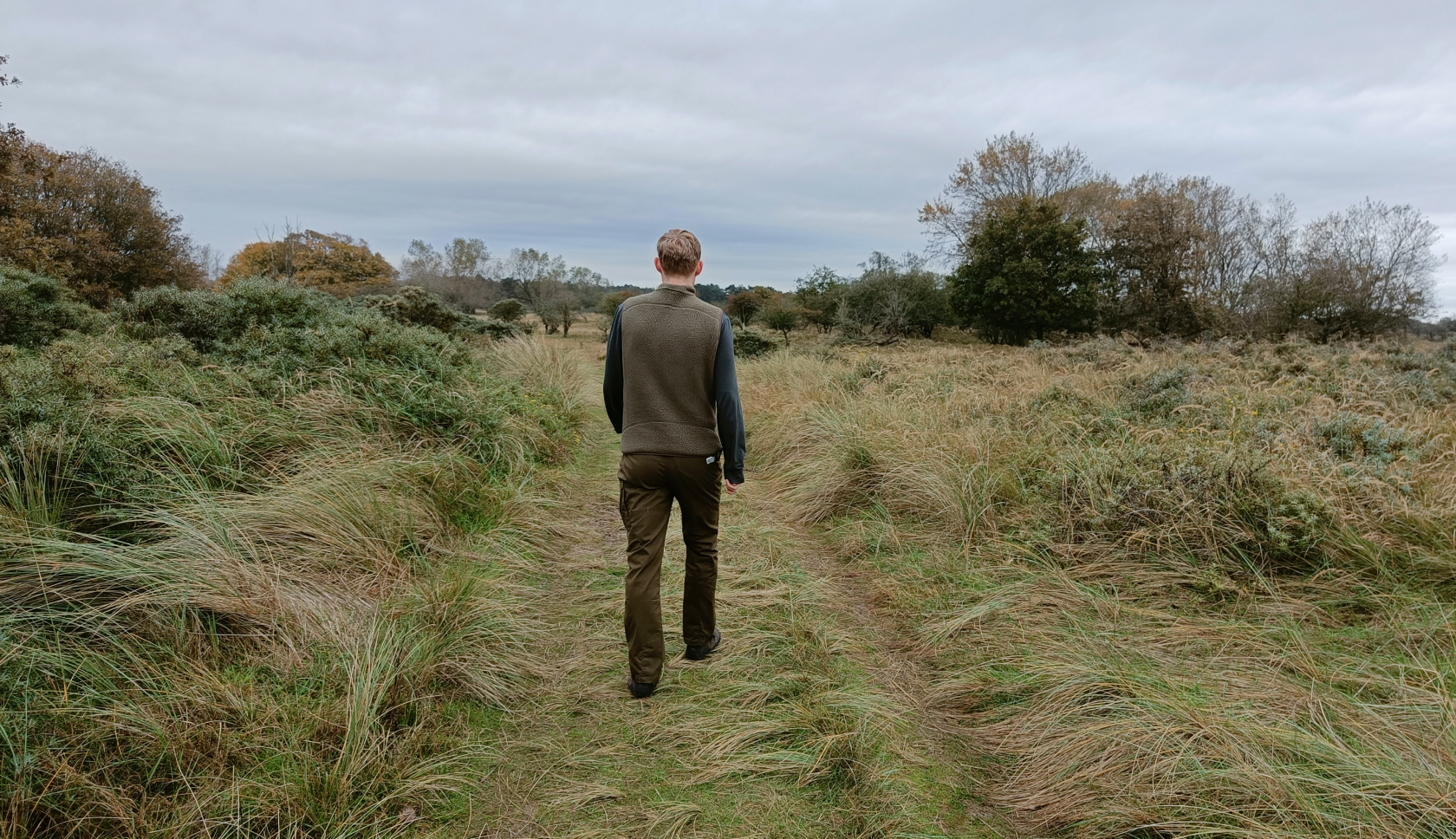 Een blauwe rugzak staat met het rugpand naar de camera in hoog gras