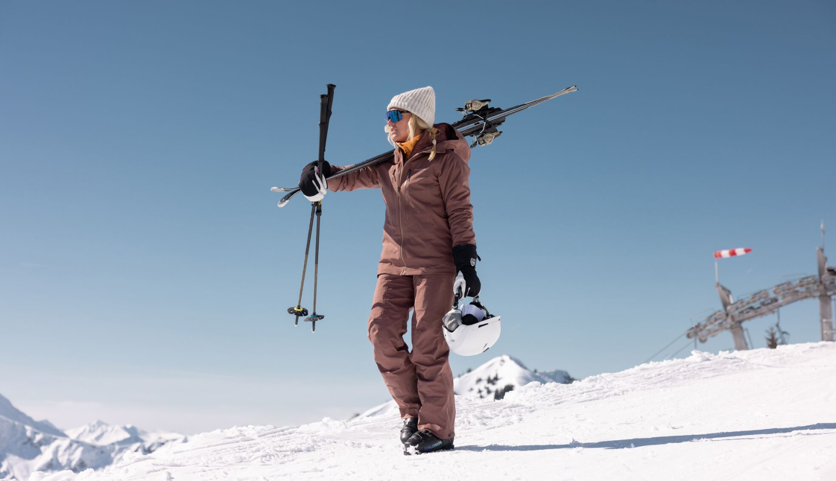 een vrouw draagt  haar ski's op de piste