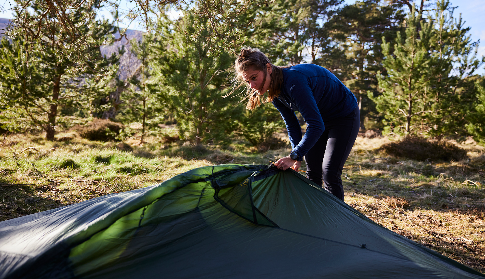 Jonge vrouw is in de natuur haar tent aan het opzetten.