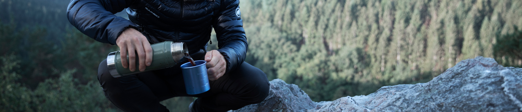 Man schenkt warme koffie uit een thermosfles